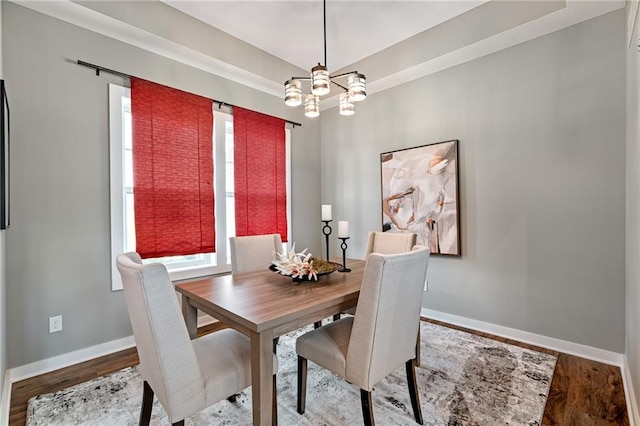dining room with baseboards, wood finished floors, and an inviting chandelier