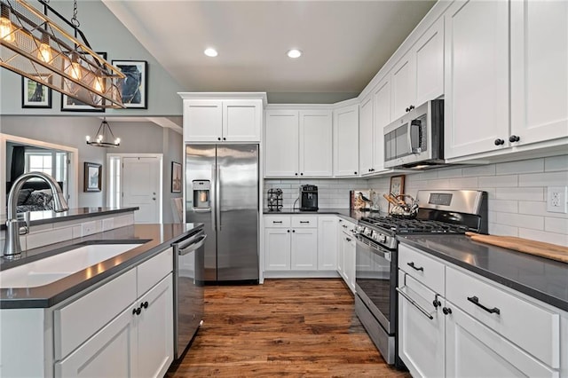 kitchen featuring a sink, appliances with stainless steel finishes, a notable chandelier, and dark countertops