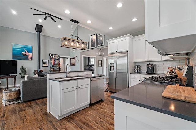 kitchen with dark wood-style flooring, dark countertops, appliances with stainless steel finishes, and a sink