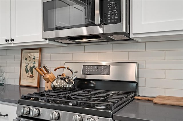 interior details featuring decorative backsplash, white cabinets, and stainless steel appliances