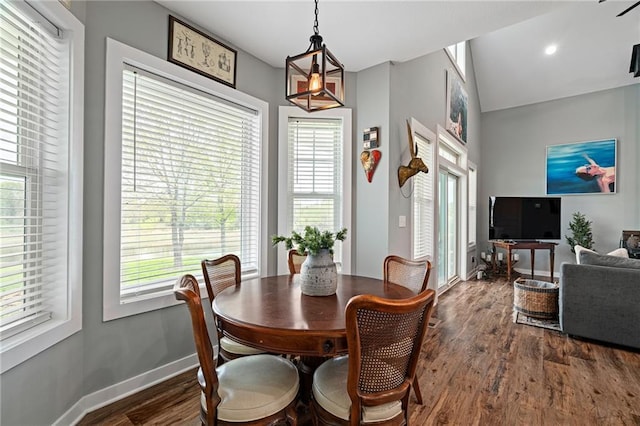 dining space with baseboards, dark wood-style floors, vaulted ceiling, and a healthy amount of sunlight
