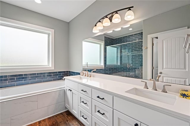 bathroom featuring wood finished floors, a sink, a bath, and a shower stall