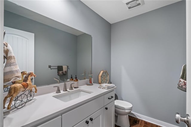 bathroom with visible vents, wood finished floors, vanity, baseboards, and toilet