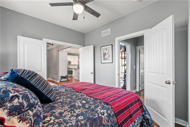 bedroom with baseboards, a ceiling fan, wood finished floors, and visible vents