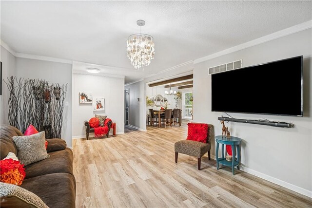  - living area with a chandelier, ornamental molding, wood finished floors, and visible vents