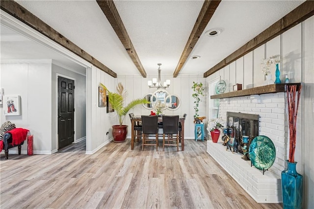  - dining room with a brick fireplace, beam ceiling, baseboards, an inviting chandelier, and light wood-style flooring