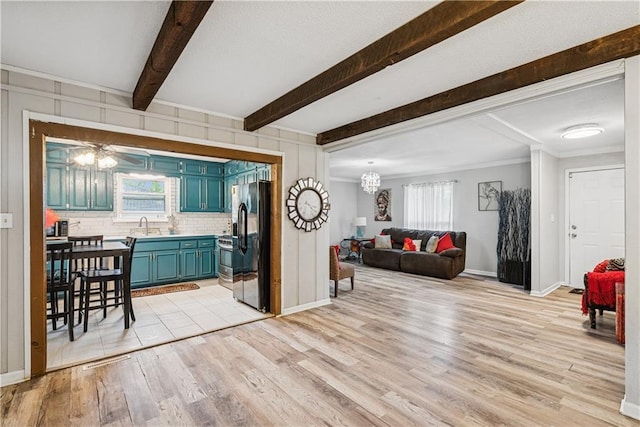  - living room featuring light wood-style floors, baseboards, beam ceiling, and a notable chandelier
