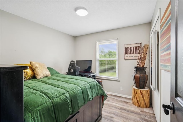  - bedroom featuring baseboards and light wood finished floors