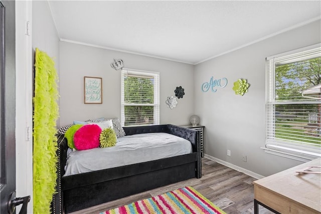  - bedroom featuring baseboards, ornamental molding, and wood finished floors