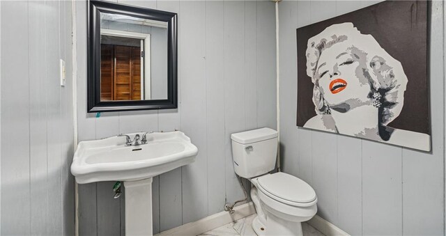  - half bathroom featuring toilet, baseboards, a sink, and marble finish floor