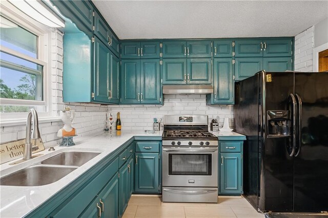  - kitchen featuring black fridge, a sink, stainless steel range with gas cooktop, backsplash, and under cabinet range hood