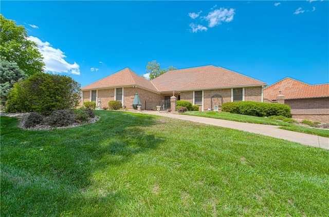 ranch-style home featuring a front lawn and brick siding