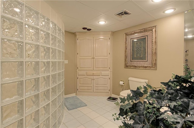 bathroom featuring toilet, a drop ceiling, tile patterned floors, visible vents, and baseboards