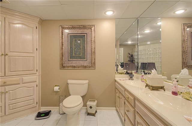 bathroom with double vanity, toilet, a sink, tile patterned floors, and baseboards