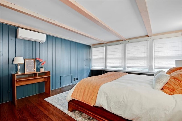 bedroom with a wall unit AC, beam ceiling, wood finished floors, and multiple windows