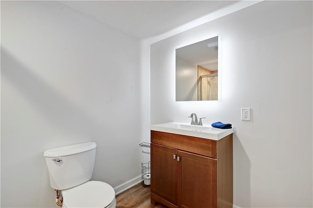 bathroom featuring toilet, vanity, wood finished floors, and baseboards