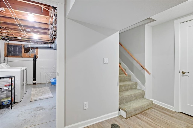 basement featuring washing machine and clothes dryer, stairway, and baseboards