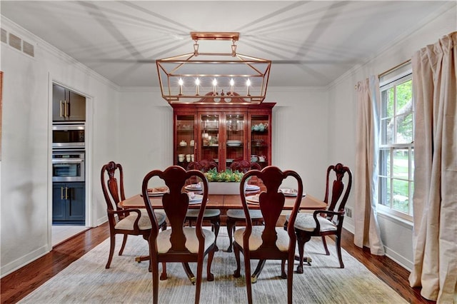 dining room featuring crown molding, baseboards, and wood finished floors