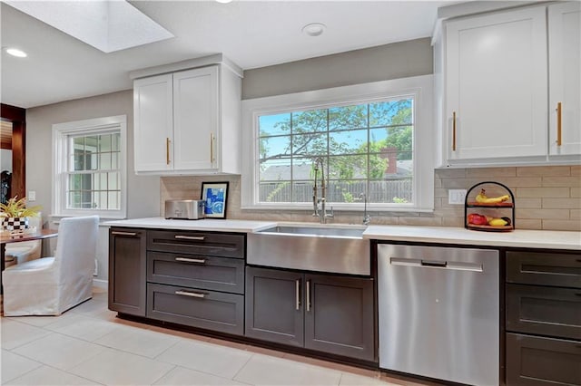 kitchen featuring stainless steel dishwasher, a sink, a skylight, light countertops, and recessed lighting