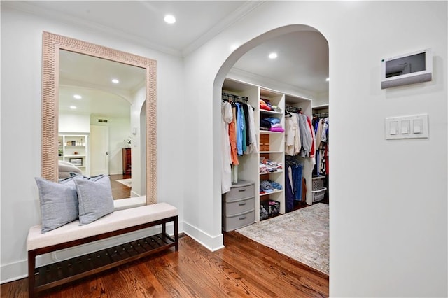hall featuring wood finished floors, baseboards, arched walkways, crown molding, and recessed lighting