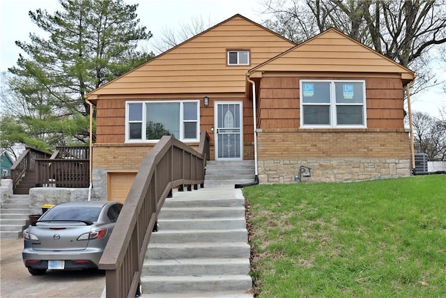3417 Jackson Ave, Kansas City, MO 64128 - view of front of house featuring an attached garage, a front yard, stairway, and brick siding