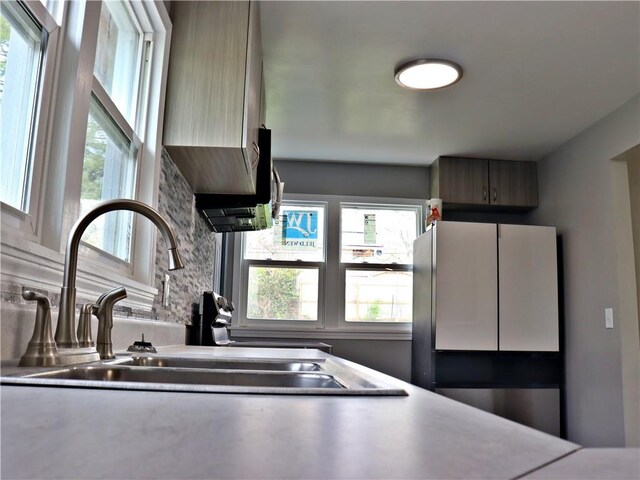 3417 Jackson Ave, Kansas City, MO 64128 - kitchen featuring a sink, decorative backsplash, and freestanding refrigerator