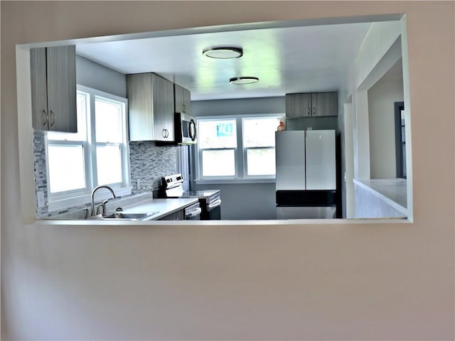 3417 Jackson Ave, Kansas City, MO 64128 - kitchen featuring a sink, appliances with stainless steel finishes, decorative backsplash, and light countertops