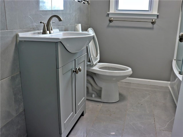 3417 Jackson Ave, Kansas City, MO 64128 - full bathroom with vanity, marble finish floor, toilet, baseboards, and a tub