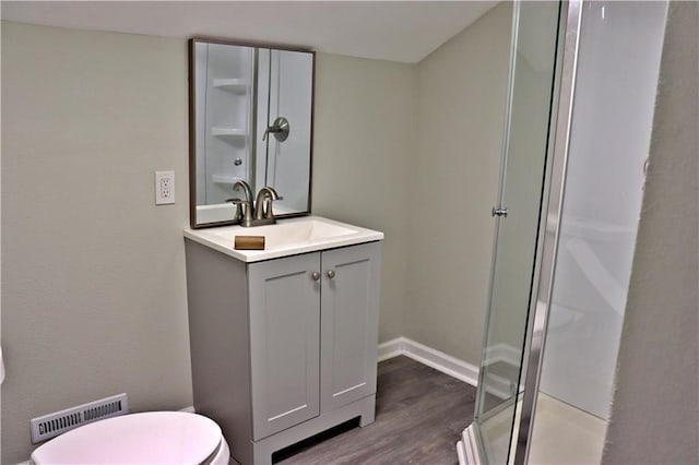 3417 Jackson Ave, Kansas City, MO 64128 - full bath with vanity, visible vents, wood finished floors, toilet, and a shower stall