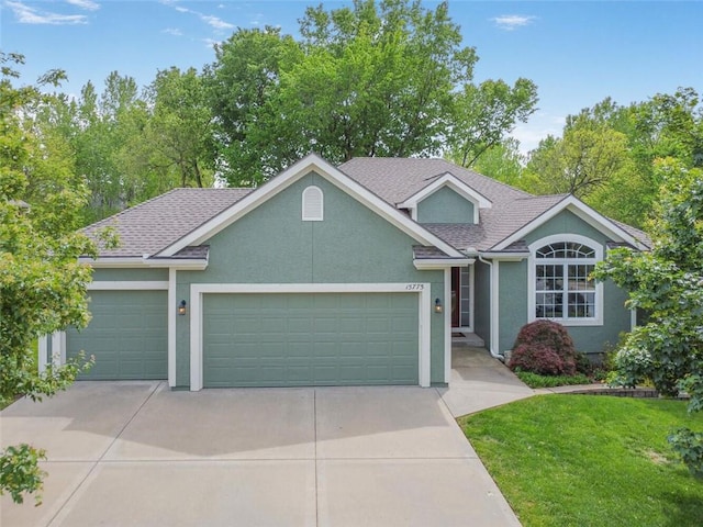 view of front of house with stucco siding, a garage, driveway, roof with shingles, and a front yard