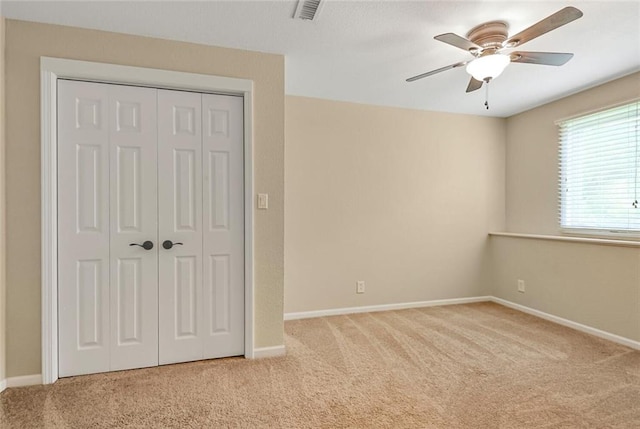unfurnished bedroom featuring carpet flooring, baseboards, a closet, and ceiling fan
