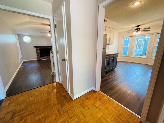 hallway featuring baseboards, a textured ceiling, and parquet flooring