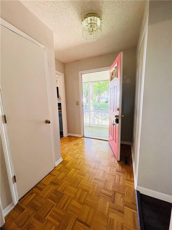doorway with baseboards and a textured ceiling