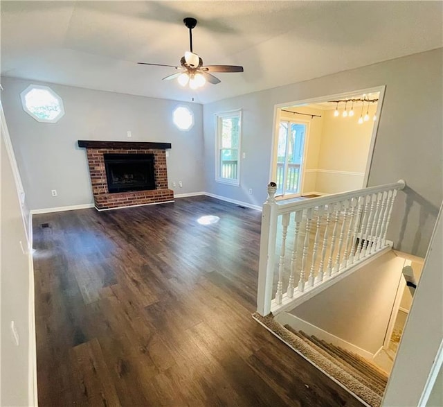unfurnished living room with baseboards, ceiling fan, a fireplace, and wood finished floors