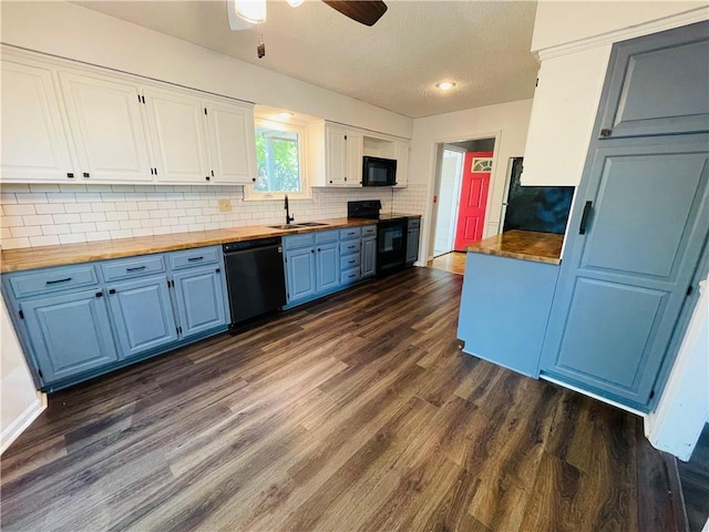 kitchen with blue cabinets, dark wood-style flooring, black appliances, and wooden counters