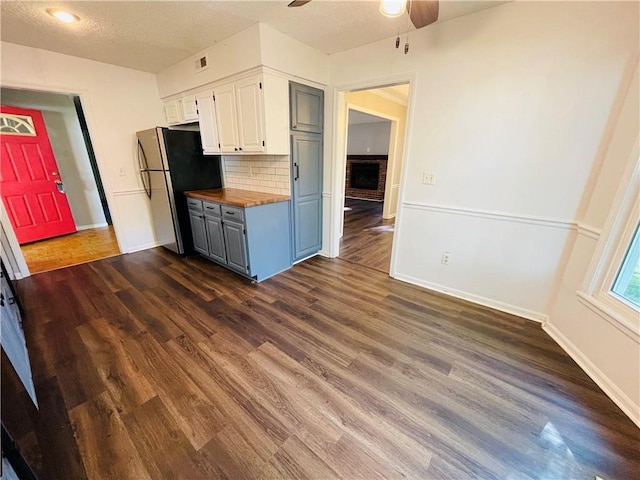 kitchen with wooden counters, a ceiling fan, tasteful backsplash, white cabinets, and freestanding refrigerator