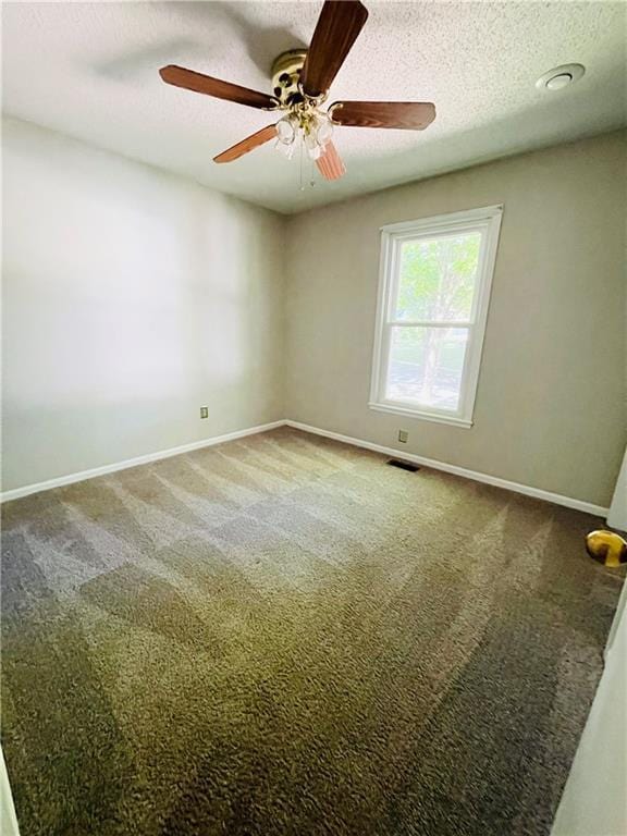 carpeted empty room with baseboards, a textured ceiling, and visible vents
