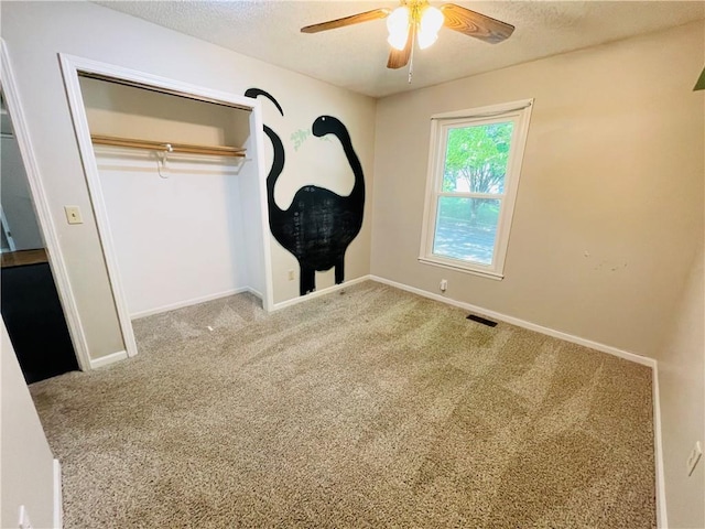 unfurnished bedroom featuring carpet floors, baseboards, a ceiling fan, and a textured ceiling
