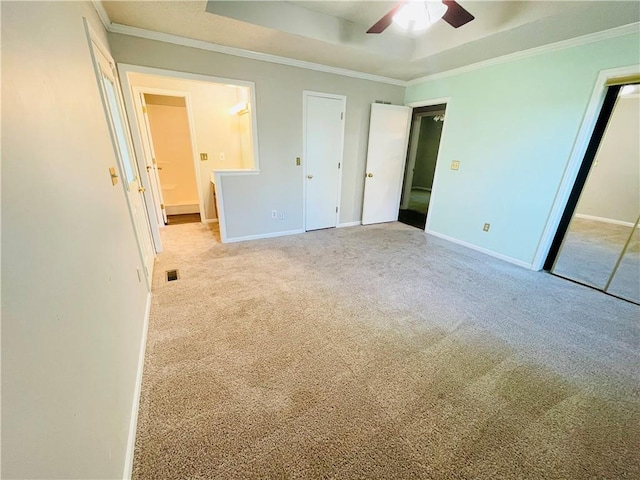 unfurnished bedroom featuring carpet floors, baseboards, a tray ceiling, visible vents, and ornamental molding