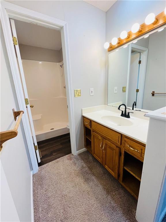 bathroom featuring vanity, baseboards, and walk in shower