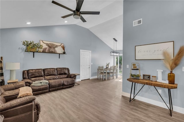 living area featuring baseboards, ceiling fan with notable chandelier, wood finished floors, and visible vents