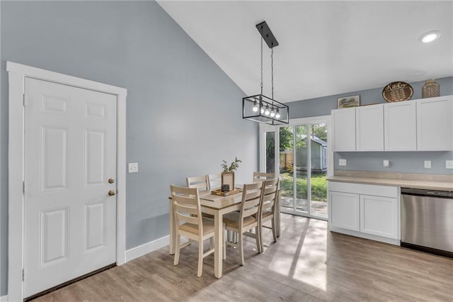 dining area with an inviting chandelier, baseboards, light wood-type flooring, and lofted ceiling