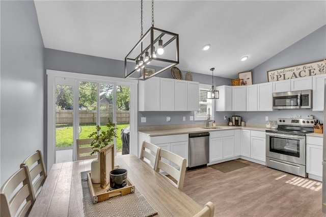 kitchen featuring lofted ceiling, light countertops, white cabinets, a sink, and stainless steel appliances