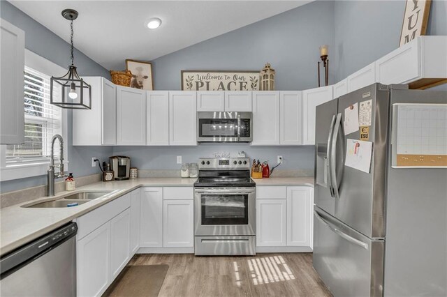 kitchen featuring vaulted ceiling, a sink, light countertops, light wood-style floors, and stainless steel appliances