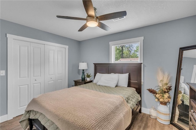 bedroom featuring baseboards, ceiling fan, wood finished floors, and a closet