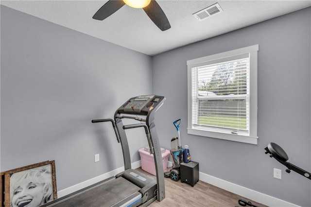 workout room featuring visible vents, wood finished floors, baseboards, a textured ceiling, and a ceiling fan