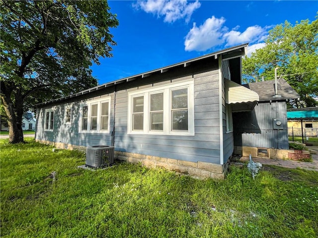 view of side of home featuring a lawn and central AC