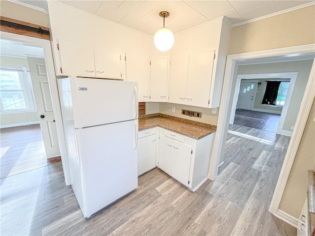 kitchen featuring light wood-style floors, white cabinets, freestanding refrigerator, and plenty of natural light