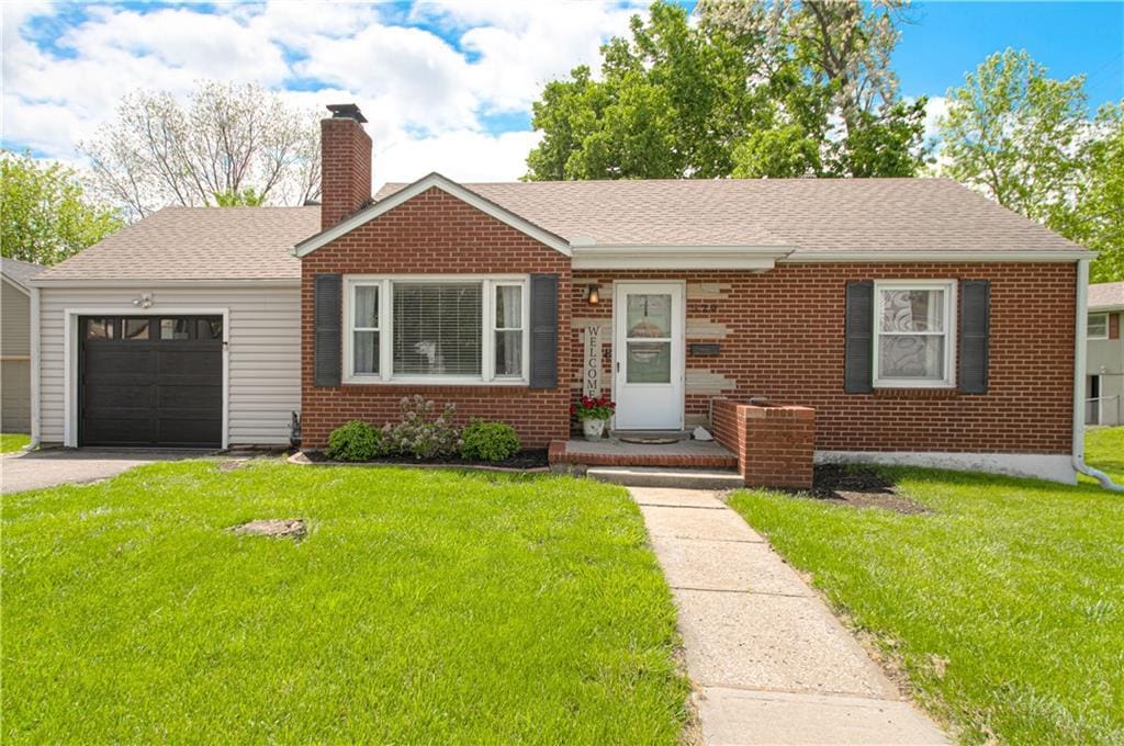 ranch-style house featuring an attached garage, aphalt driveway, a chimney, and brick siding