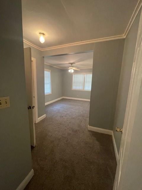 2120 68th Ter, Kansas City, MO 64132 - empty room featuring crown molding, baseboards, ceiling fan, and dark colored carpet